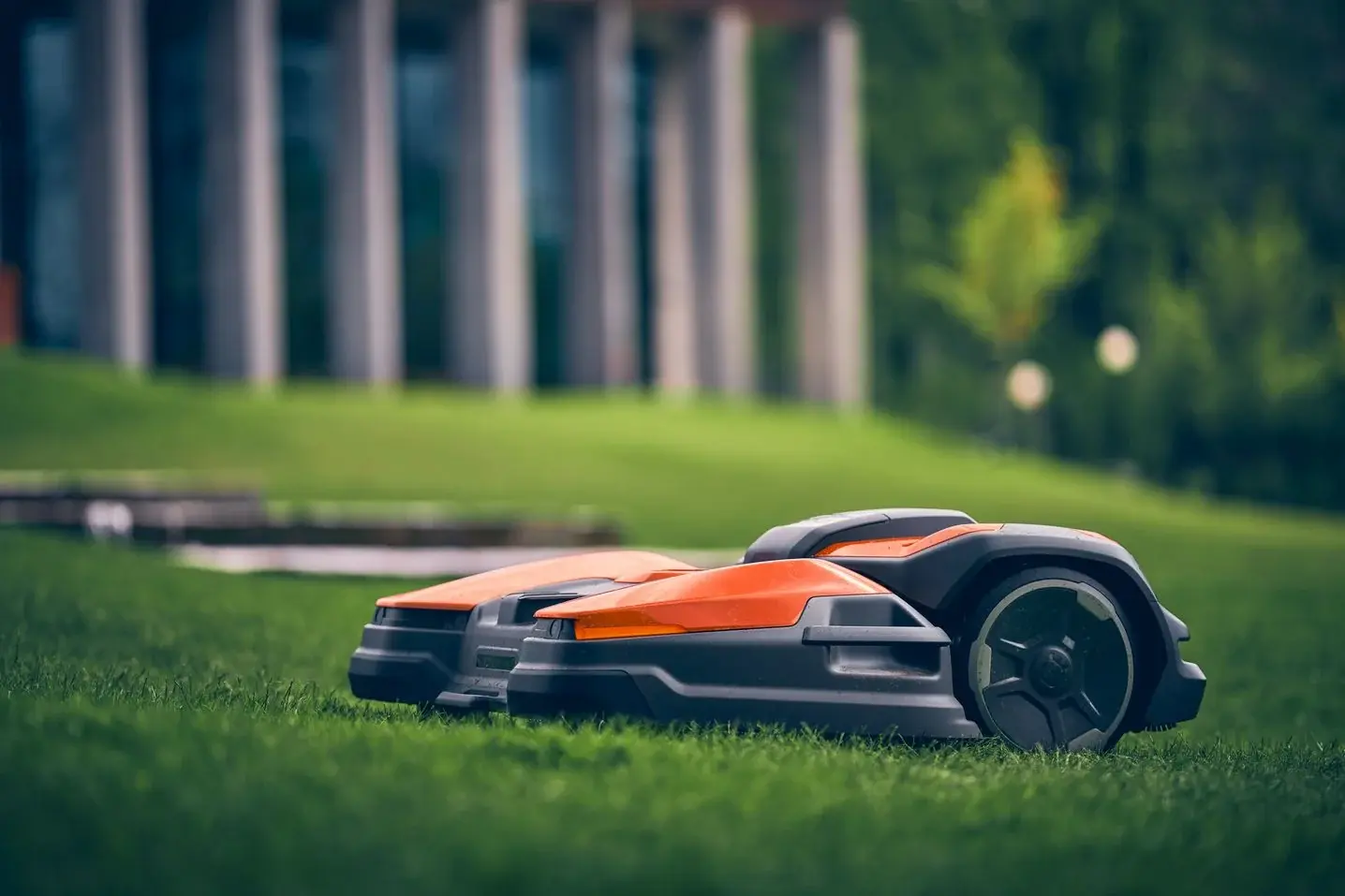 A Husqvarna CEORA robotic mower cutting a lawn, seen low from the grass
